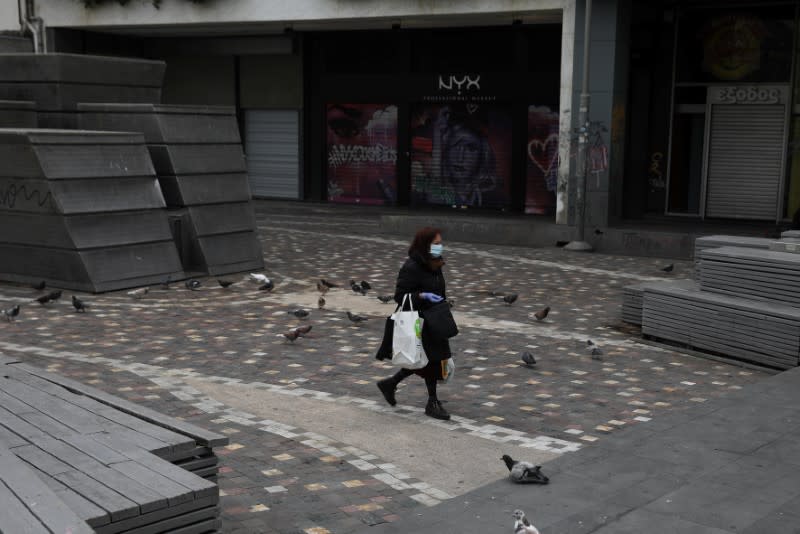 A woman wearing a protective face mask makes her way on Monastiraki square, following an outbreak of the coronavirus disease (COVID-19), in Athens