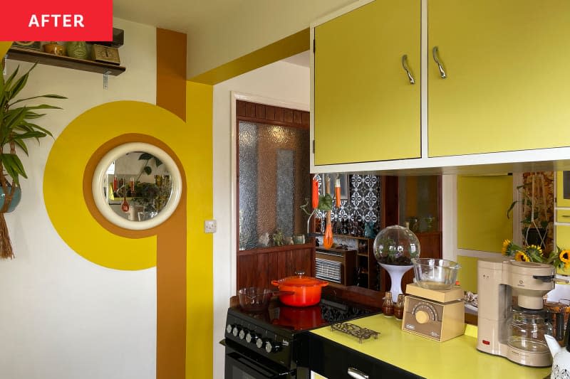 Yellow retro cabinets in kitchen with yellow and brown decal on wall after renovation.