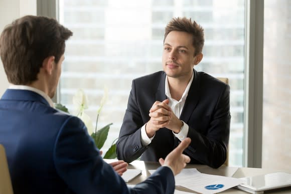 Two men in suits sitting across from each other