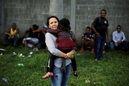 A Honduran woman carries her daughter as they wait to leave with a new caravan of migrants, set to head to the United States, at a bus station in San Pedro Sula, Honduras, January 14, 2019. REUTERS/Jorge Cabrera