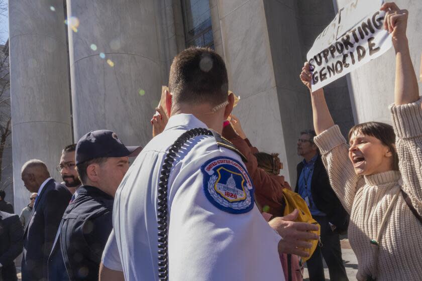 Secretary of Defense Lloyd Austin, at far left, is escorted to a vehicle after speaking to the House Armed Services Committee, Thursday, Feb. 29, 2024, as Code Pink protesters of the Israel-Hamas war hold up signs including one saying "Austin Stop Supporting Genocide," on Capitol Hill in Washington. (AP Photo/Jacquelyn Martin)