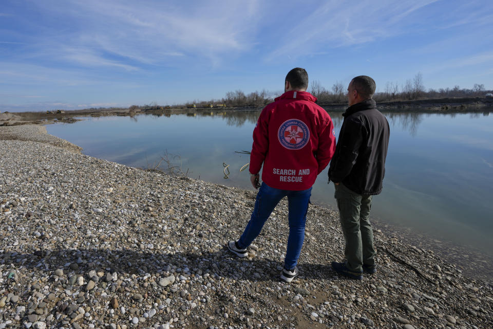 Mountain Rescue Service members Mladen Rosic, left, and Nenad Jovanovic stand on a bank of the Drina River near the village of Amajlije, eastern Bosnia, Sunday, Feb. 4, 2024. In several cities along this river between Bosnia and Serbia, simple, durable gravestones now mark the final resting places of dozens of refugees and migrants who drowned in the area while trying to reach Western Europe.(AP Photo/Darko Vojinovic)