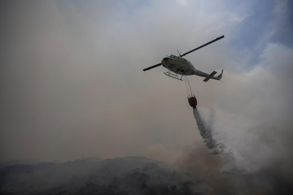 A helicopter drops water as firefighters battle wildfires in Pringle Bay, near Cape Town South Africa, Tuesday, Jan. 30 2024. Residents have been evacuated as wildfires swept down off surrounding mountains and burned out of control. (AP Photo)