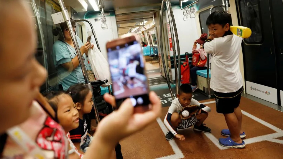 Children pose on a sports-themed Metro train in Taipei, marking the city's status as host of the 2017 Summer Universiade, an international sports event for university athletes. - Tyrone Siu/Reuters