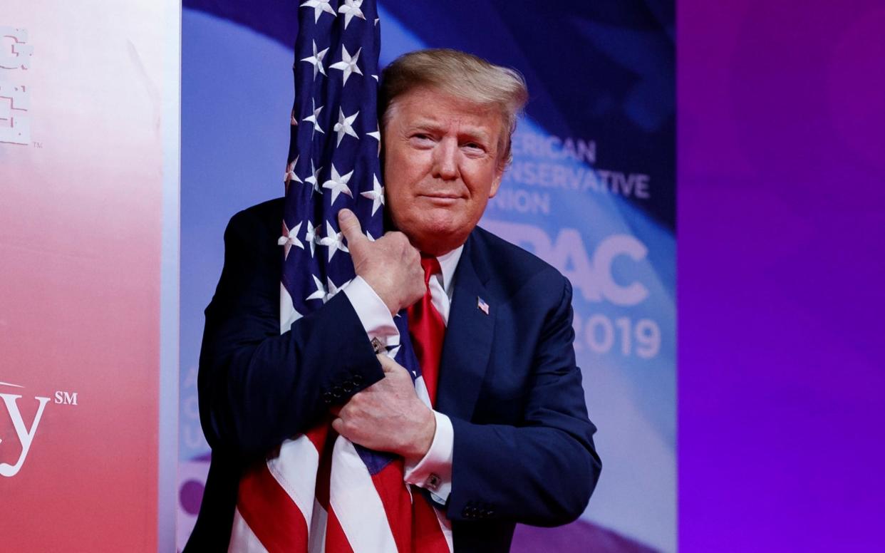 President Donald Trump hugs the American flag as he arrives to speak at Conservative Political Action Conference, CPAC 2019 - AP