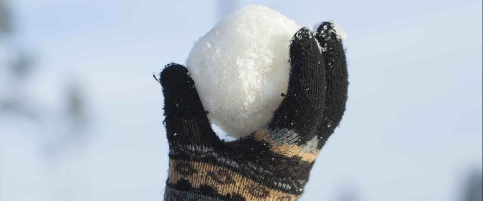 Snowball in hand on blue sky background