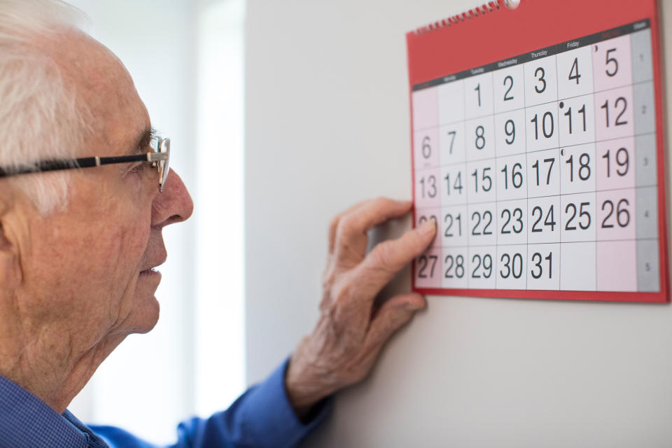 Senior man looking at a wall calendar