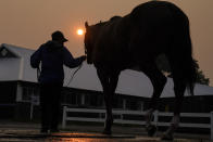A handler leads a horse back into the stables as the sun is obscured by haze caused by Canadian wildfires ahead of the Belmont Stakes horse race, Thursday, June 8, 2023, at Belmont Park in Elmont, N.Y. Training was cancelled for the day due to poor air quality. (AP Photo/John Minchillo)