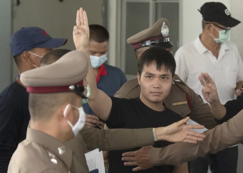 Tattep Ruangprapaikitseree raises a three-finger salute, a symbol of resistance, as he leaves the Samranrat police station.