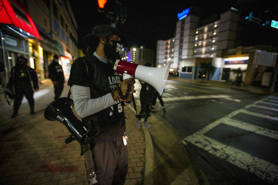 Aubrey "Japharii" Jones, president of Black Lives Matter uses a bull horn to speak Saturday March 27, 2021 in Virginia Beach, Va.. Overnight shootings near the Atlantic oceanfront in Virginia Beach left two people dead and eight wounded in a scene described by authorities on Saturday as “very chaotic.” (AP Photo/John C. Clark)