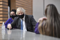 Britain's Prime Minister Boris Johnson meets with Year 11 students in the canteen during a visit to Accrington Academy in Accrington, England, Thursday, Feb. 25, 2021, as they prepare for the return of all pupils on March 8. (Anthony Devlin/Pool Photo via AP)