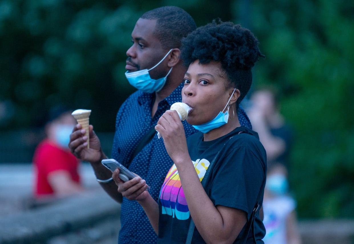 <span class="caption">A woman eats ice cream at Gantry Plaza State Park, Long Island City on May 30, 2020 in New York City. All 50 states have begun to reopen after weeks of stay-at-home measures.</span> <span class="attribution"><a class="link " href="https://www.gettyimages.com/detail/news-photo/woman-pulls-down-her-mask-to-eat-ice-cream-at-gantry-plaza-news-photo/1236831874?adppopup=true" rel="nofollow noopener" target="_blank" data-ylk="slk:Alexi Rosenfeld/Getty Images;elm:context_link;itc:0;sec:content-canvas">Alexi Rosenfeld/Getty Images</a></span>