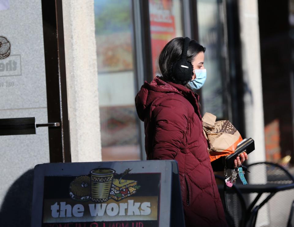 A woman picks up an order at The Works Cafe in Portsmouth Monday, Jan. 10, 2022, entering and exiting wearing a mask in compliance with a city public health directive.