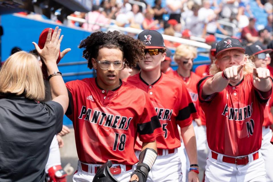 Pleasure Ridge Park’s Ravon Lee (18) celebrates scoring a run along with his teammates in the dugout during their state baseball semifinals game against Trinity at Kentucky Proud Park on Friday.
