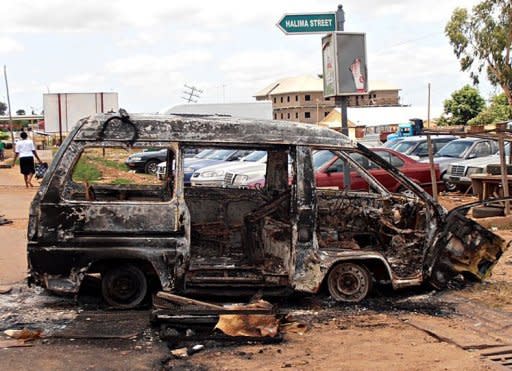 A woman walks near a minibus burnt by an angry mob in reaction to suicide bomb attacks on the Shallom Church of God during church service on Sunday in the Trikania neighbourhood in Kaduna. Fresh explosions and gunfire rocked a northeastern Nigerian city on Monday, a day after suicide attacks claimed by Islamists and reprisal violence by rampaging Christian mobs left 52 people dead