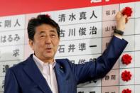 Japan's Prime Minister Shinzo Abe puts a rosette on the name of a candidate who is expected to win the upper house election at the LDP headquarters in Tokyo