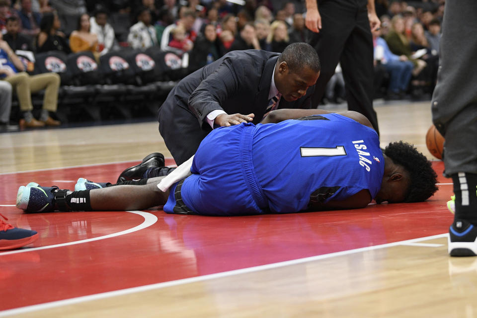 Orlando Magic forward Jonathan Isaac (1) receives attention after he sustained an injury during the first half of the team's NBA basketball game against the Washington Wizards, Wednesday, Jan. 1, 2020, in Washington. (AP Photo/Nick Wass)