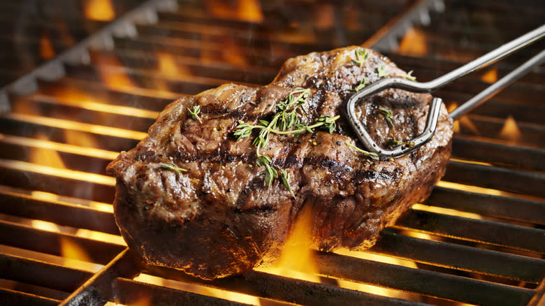 Tongs removing steak from grill