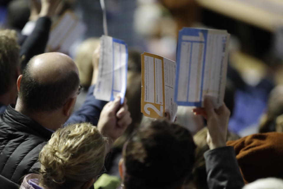 FILE - Precinct 68 Iowa Caucus voters seated in the Biden section hold up their first votes of the caucus as they are counted at the Knapp Center on the Drake University campus in Des Moines, Iowa, Feb. 3, 2020. (AP Photo/Gene J. Puskar, File)