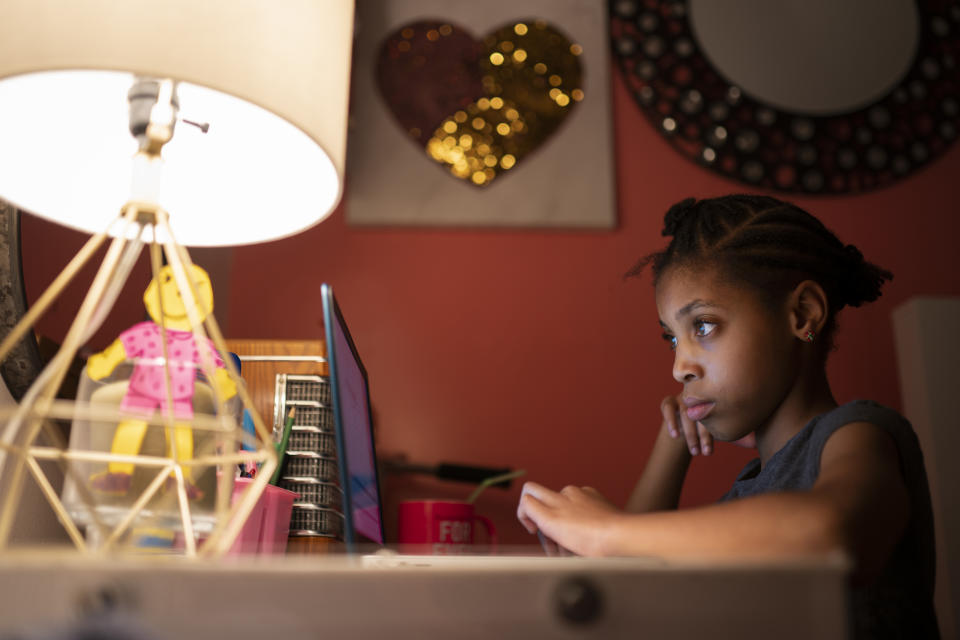 Abigail Schneider, 8, completes a level of her learning game on a laptop in her bedroom, Wednesday, Dec. 8, 2021, in the Brooklyn borough of New York. As more families pivot back to remote learning for quarantines and school closures, reliable, consistent access to devices and home internet remains elusive for many students who need them to keep up with their schoolwork. (AP Photo/John Minchillo)