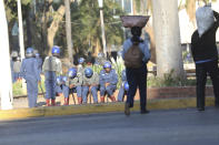 People walk past armed riot police in Harare, Friday, Aug. 16, 2019. Zimbabwe's police patrolled the streets of the capital Friday morning while many residents stayed home fearing violence from an anti-government demonstration planned by the opposition. (AP Photo/Tsvangirayi Mukwazhi)