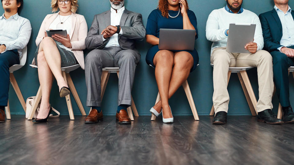 Cropped studio shot of a group of a diverse group of businesspeople using wireless devices while waiting in line.