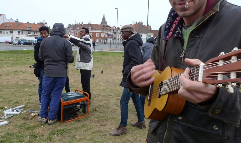 A man plays a ukelele in Calais where French President Emmanuel Macron will head Tuesday to meet migrants seeking to reach Britain