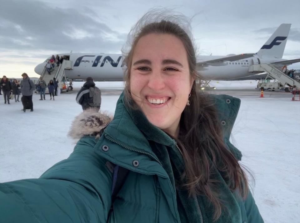 The author in a green jacket in front of a Finnair plane in the winter.