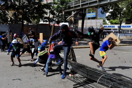 Demonstrators jump over a barricade while clashing with riot security forces during a strike called to protest against Venezuelan President Nicolas Maduro's government in Caracas, Venezuela, July 20, 2017. REUTERS/Marco Bello