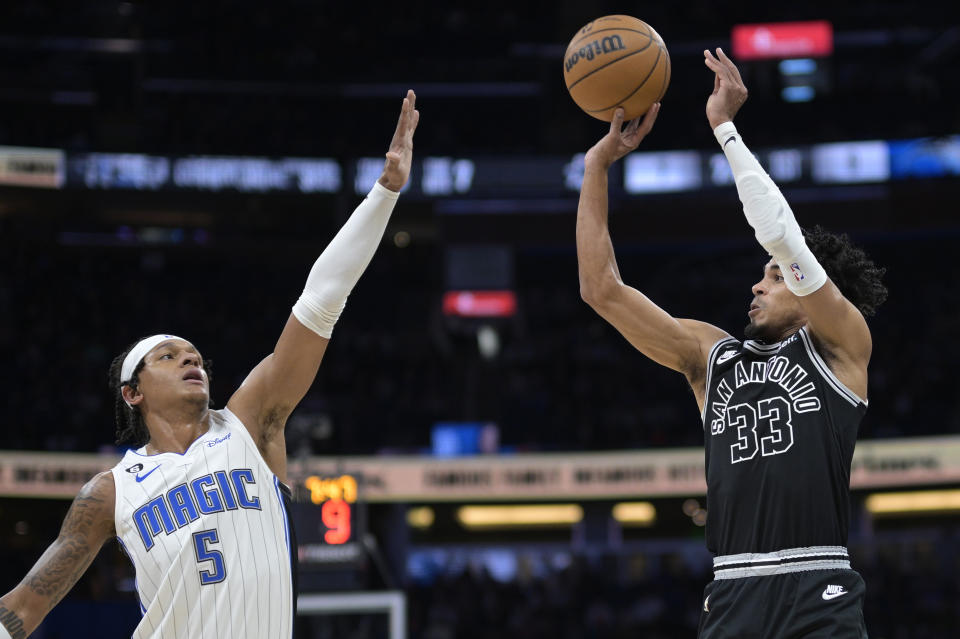 San Antonio Spurs guard Tre Jones (33) shoots in front of Orlando Magic forward Paolo Banchero (5) during the first half of an NBA basketball game Friday, Dec. 23, 2022, in Orlando, Fla. (AP Photo/Phelan M. Ebenhack)