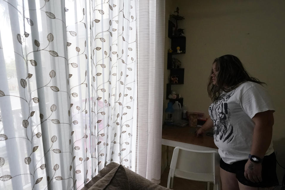 A mother of four looks out the window from her apartment, Aug. 24, 2023, in Homestead, Fla. The Honduran native worked as a house painter shortly after arriving in the U.S. in 2021. Fear has forced many undocumented workers to leave the state following a new law signed by Florida Gov. Ron DeSantis. (AP Photo/Marta Lavandier)