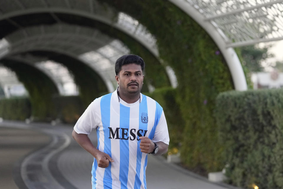 A fan in a Messi jersey runs at Al Gharafa Park in Doha, Qatar, Thursday, Nov. 24, 2022. Qatar unveiled a plan last October to cut its emissions by a quarter by 2030. Then, Russia invaded Ukraine and made the Persian Gulf nation's liquid natural gas only more sought after. Demand for fossil fuels has brought immense wealth to Qatar, but in the coming decades, it could also make one of the world's hottest places unlivable. (AP Photo/Abbie Parr)