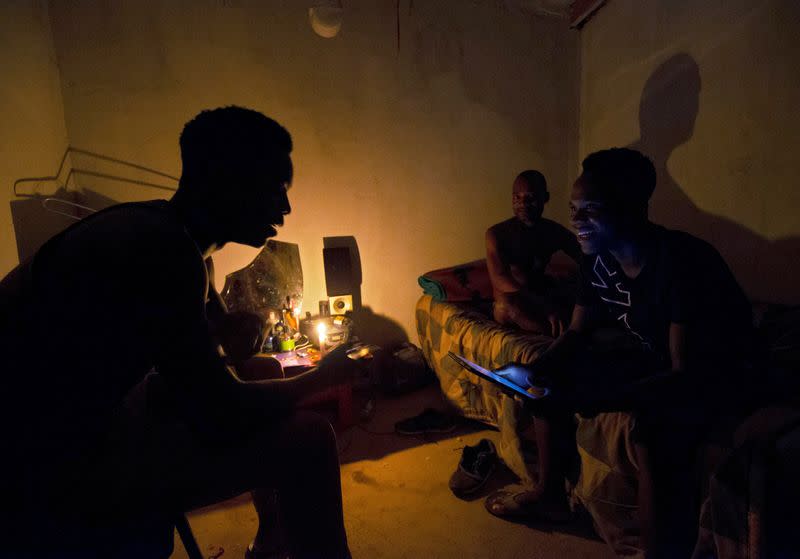 FILE PHOTO: Friends talk by candle light during load shedding in Embo