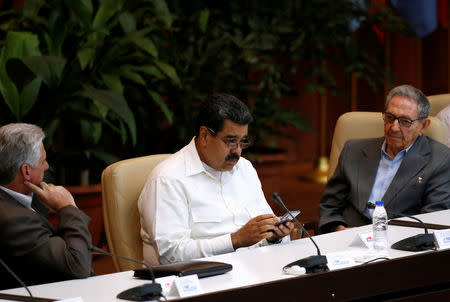 FILE PHOTO: Venezuela's President Nicolas Maduro (C) uses his phone as his Cuban counterpart Miguel Diaz-Canel (L) and Cuba's former President Raul Castro look on during the Sao Paulo Forum, in Havana, Cuba, July 17, 2018.REUTERS/Stringer/File Photo