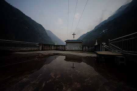 A church is reflected in a puddle during Sunday mass in an ethnic Lisu village in Fugong county of Nujiang Lisu Autonomous Prefecture in Yunnan province, China, March 25, 2018. REUTERS/Aly Song