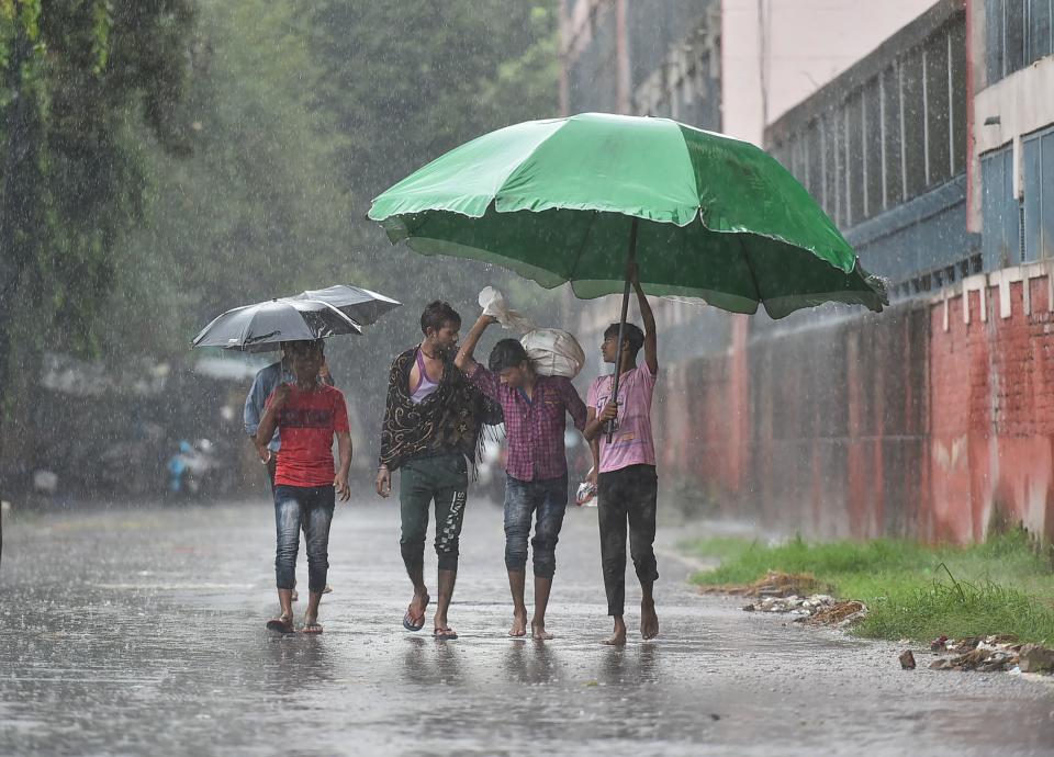 <div class="paragraphs"><p>Pedestrians hold a large umbrella as they walk in the rain at Connaught Place in New Delhi on Sunday, 17 October.</p></div>