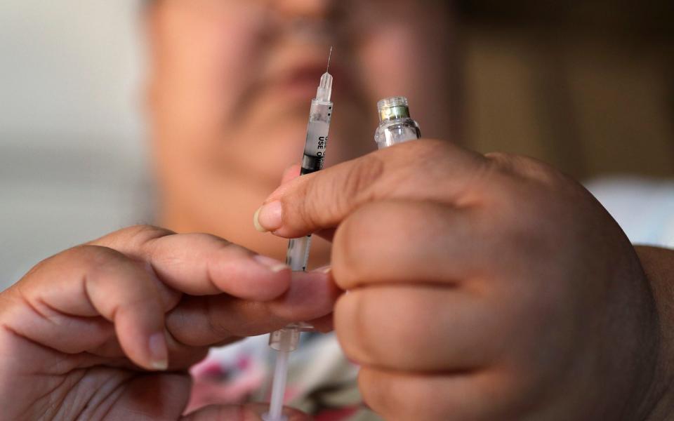 A woman with Type 2 diabetes prepares to inject herself with insulin - John Locher/AP Photo