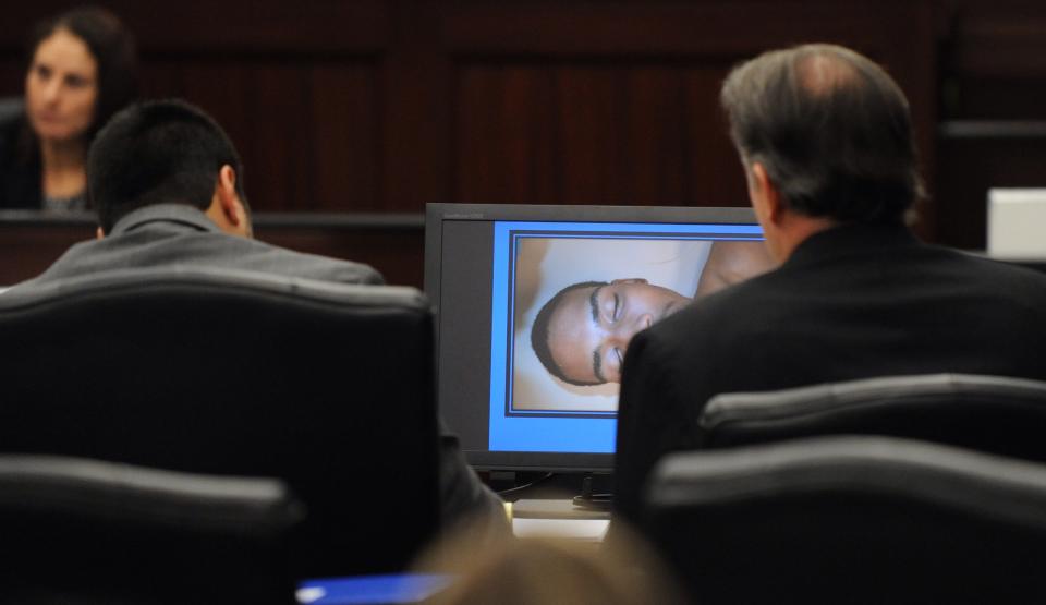 Michael Dunn, right, and his defense attorney Cory Strolla view a medical examiner's photo of Jordan Davis during Dunn's trial in Jacksonville, Fla., Monday, Feb. 10, 2014. The prosecution has rested in the trial of Dunn charged with killing Davis following an argument over loud music outside a Jacksonville convenience store. (The Florida Times-Union, Bob Mack, Pool)
