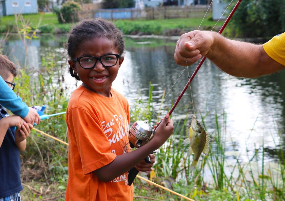 A girl catches a small fish during a fishing derby along the Ohio & Erie Canal.