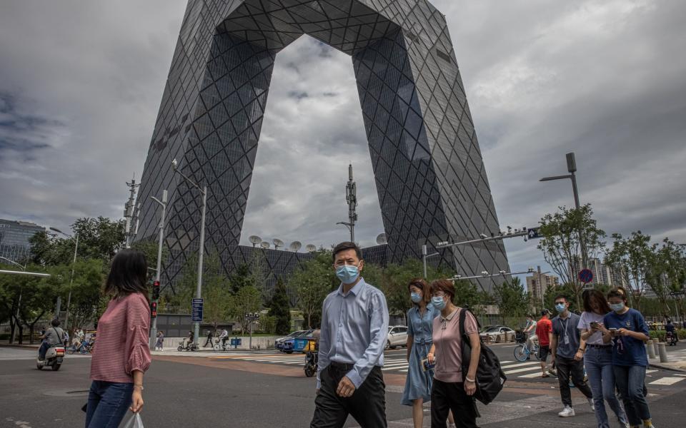 People wearing face masks cross the road in the Central Business District (CBD) area of Beijing, - ROMAN PILIPEY/Shutterstock