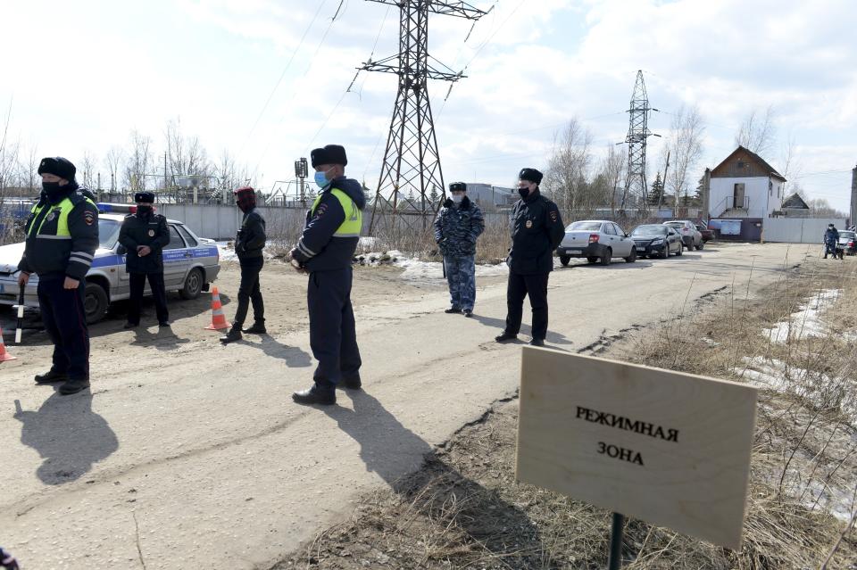 FILE - Police officers in face masks to protect against the coronavirus stand guard at Penal Colony No. 2 in Pokrov in the Vladimir region, 85 kilometers (53 miles) east of Moscow, Russia, on April 6, 2021. The sign outside the colony, known for its strict conditions, reads "Security zone." Former inmates, their relatives and human rights advocates paint a bleak picture of Russia’s prison system that is descended from the USSR's gulag. For political prisoners, life inside is a grim reality of physical and psychological pressure. (AP Photo/Denis Kaminev, File)