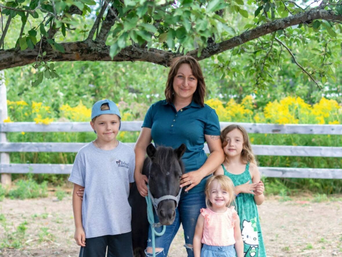 Aimée Hutchinson and her three children, from left, Chance, Ivy-Jane and Esmee with one of their miniature horses, Charlotte. (Submitted by Aimee Hutchinson - image credit)