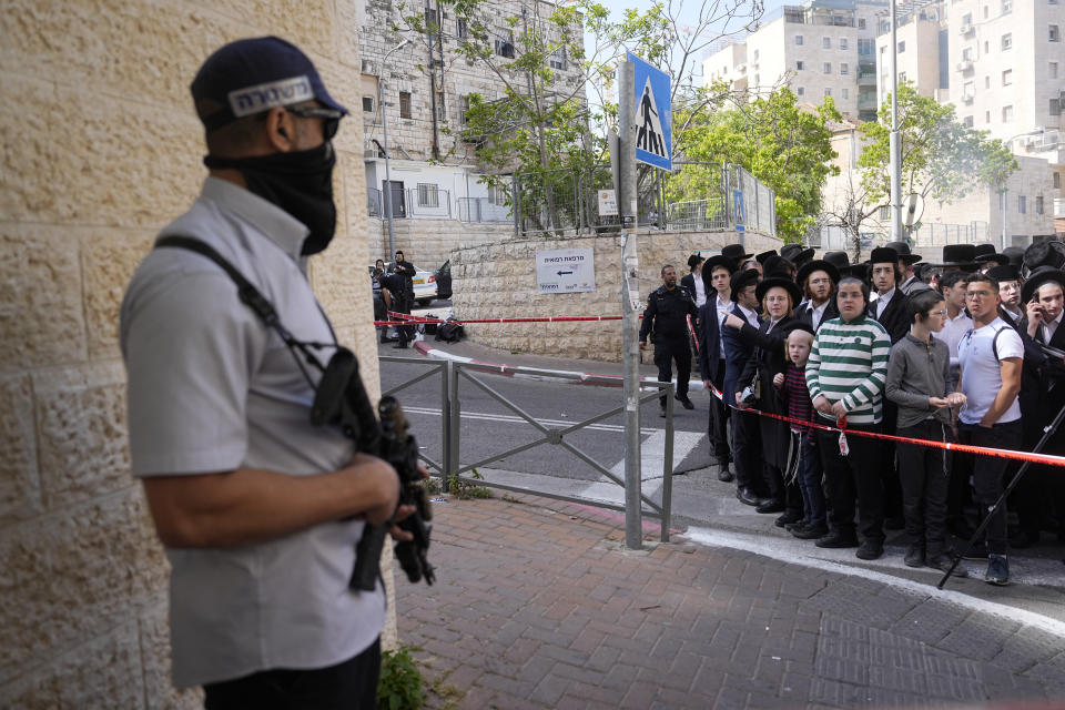 Ultra-Orthodox Jewish residents watch Israeli police work at the scene of a suspected ramming attack that wounded three people on the eve of the Jewish holiday of Passover, in Jerusalem, Monday, April 22, 2024. Israeli police say a car slammed into pedestrians in Jerusalem on Monday, wounding three people lightly in an apparent attack. (AP Photo/Ohad Zwigenberg)