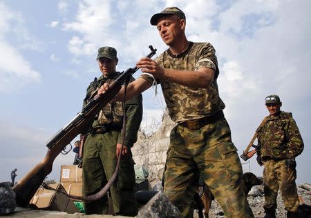 A Pro-Russian separatist inspects a gun at a destroyed war memorial at Savur-Mohyla, a hill east of the city of Donetsk, August 28, 2014. REUTERS/Maxim Shemetov