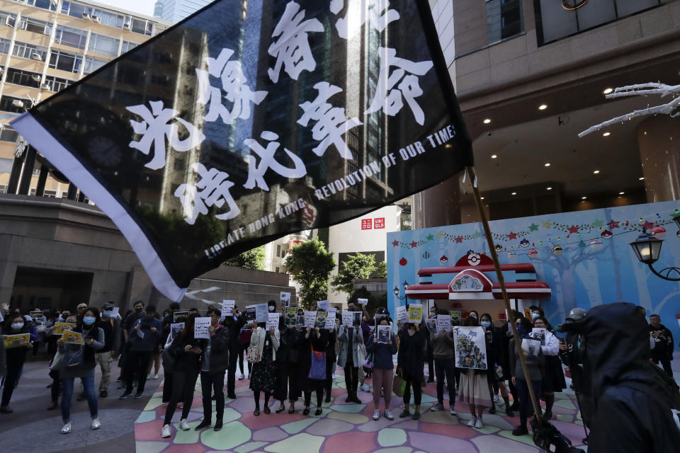 A pro-democracy protester waves a flag as protesters and office workers stage a protests on a street at Causeway Bay in Hong Kong, Wednesday, Dec. 11, 2019. Hong Kong Chief Executive Carrie Lam on Tuesday again ruled out further concessions to protesters who marched peacefully in their hundreds of thousands this past weekend, days before she is to travel to Beijing for regularly scheduled meetings with Communist Party leaders. (AP Photo/Mark Schiefelbein)