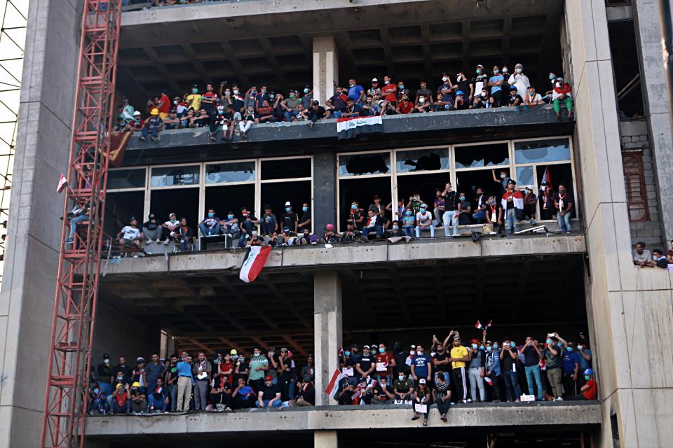 Anti-government protesters stand on a building near Tahrir Square during ongoing protests in Baghdad, Iraq, Wednesday, Oct. 30, 2019. (AP Photo/Khalid Mohammed)