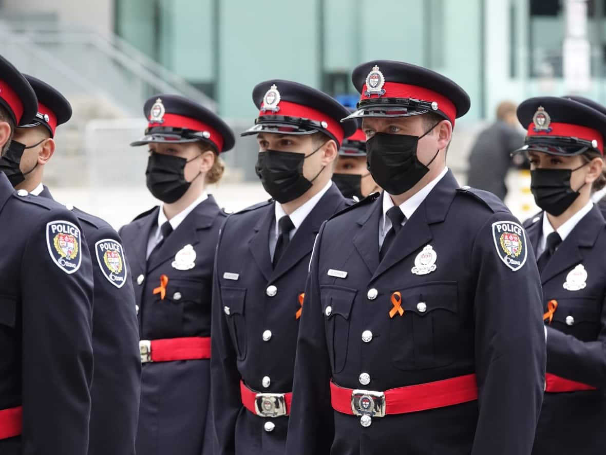 New Ottawa police recruits are seen at a badge ceremony last month. Both Mayor Jim Watson and Coun. Keith Egli, chair of the city's board of health, want the police force take a second look at its COVID-19 vaccine policy. (Francis Ferland/CBC - image credit)