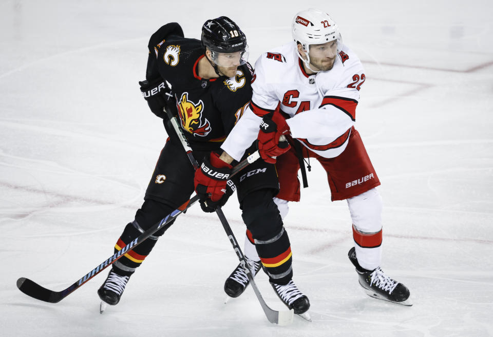 Carolina Hurricanes defenseman Brett Pesce, right, checks Calgary Flames forward Jonathan Huberdeau, left, during third-period NHL hockey game action in Calgary, Alberta, Thursday, Dec. 7, 2023. (Jeff McIntosh/The Canadian Press via AP)