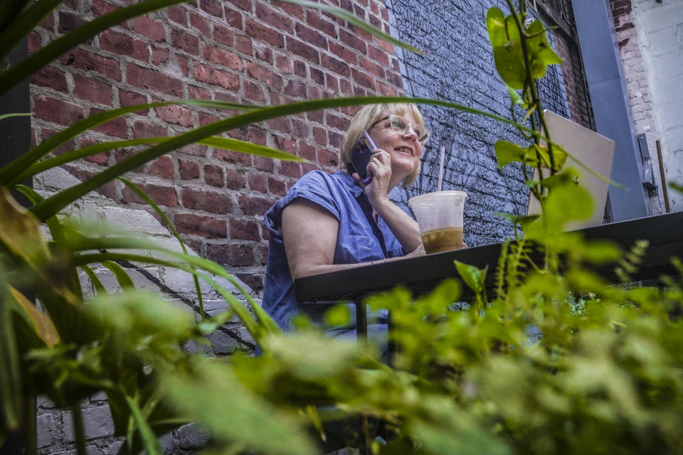 Wedding photographer Jonica Moore works from a Brooklyn cafe where she sometimes edits her wedding assignments, Friday, July 21, 2023, in New York. Moore said that adding more social content to packages will likely require her to hire another person to help with weddings. (AP Photo/Bebeto Matthews)