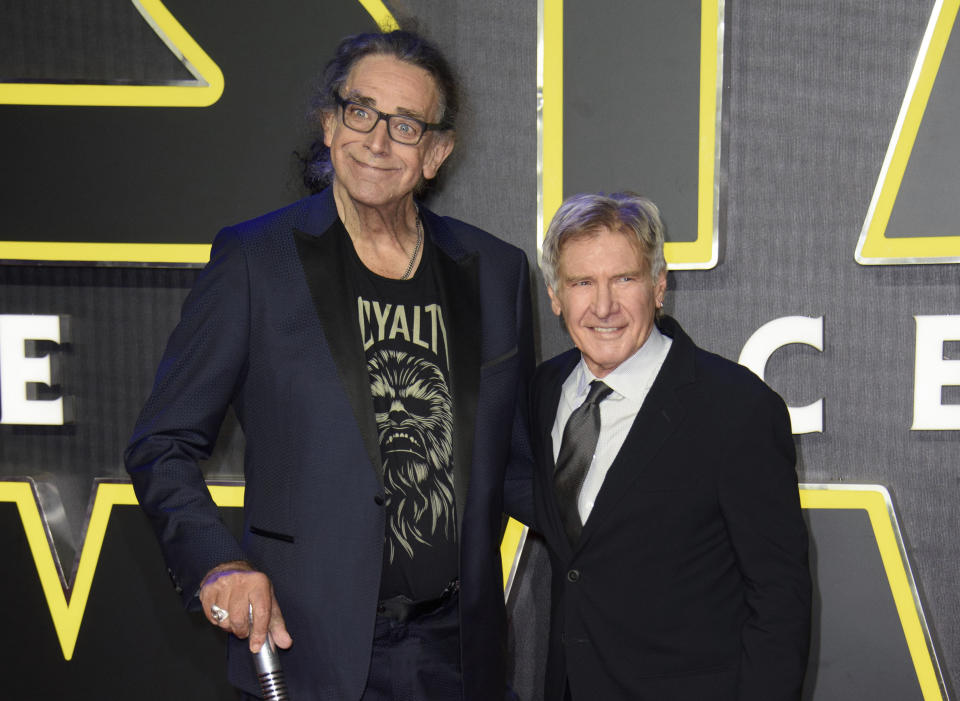 RETRANSMISSION TO CORRECT DAY AND DATE OF DEATH - FILE - This Dec. 16, 2015 file photo shows Peter Mayhew, left, and Harrison Ford at the European premiere of the film 'Star Wars: The Force Awakens ' in London. Mayhew, who played the rugged, beloved and furry Wookiee Chewbacca in the “Star Wars” films, has died. Mayhew died at his home in north Texas on Tuesday, April 30, 2019 according to a family statement. He was 74. No cause was given. (Photo by Jonathan Short/Invision/AP, File)